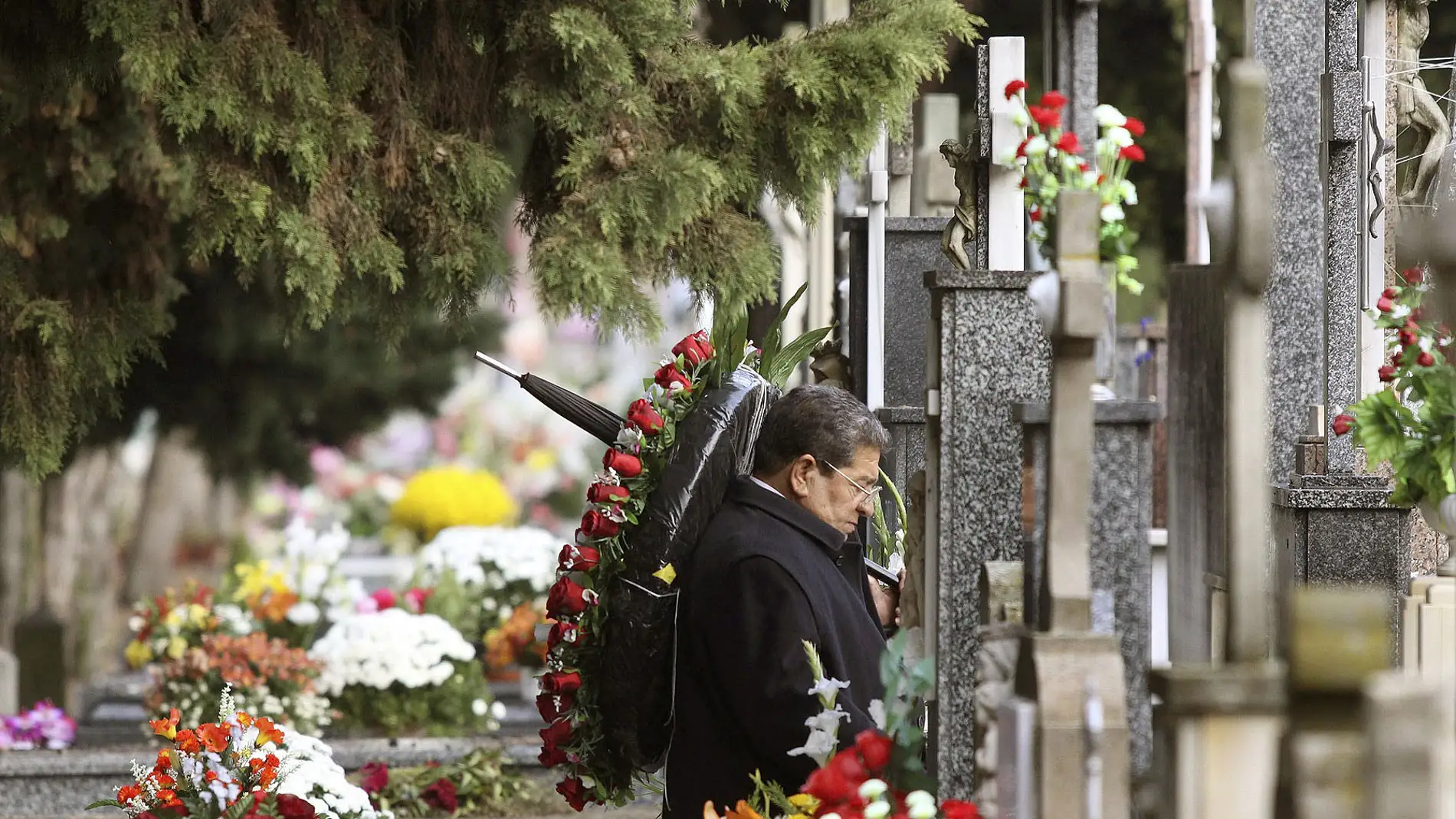 Un hombre ante una tumba en un cementerio