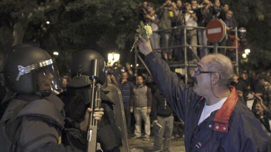 Un manifestante con una flor ante un antidisturbio