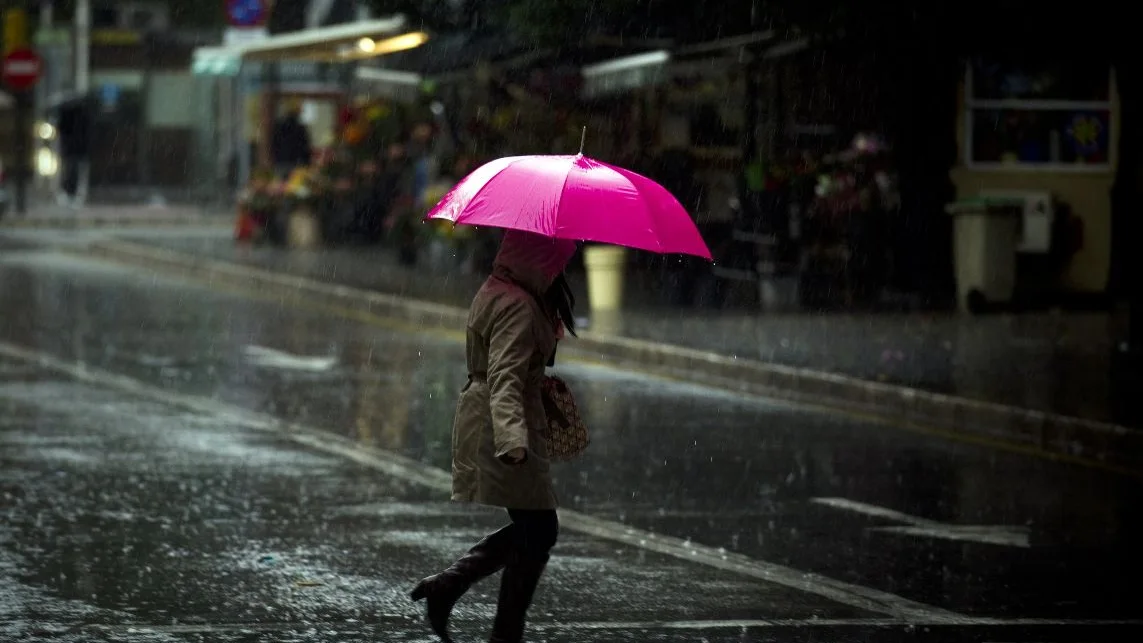Una malagueña se protege de la lluvia con su paraguas Una malagueña se protege de la lluvia con su paraguas