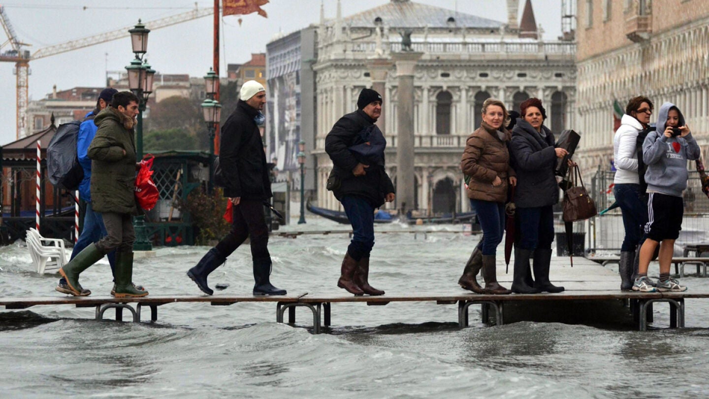 Varias personas caminan por un puente improvisado en Venecia, Italia, inundada por la marea alta. 