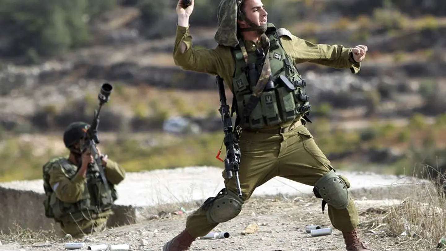 Soldado israelí lanza una granada de aturdimiento a los manifestantes palestinos en Bet Omar Soldado israelí lanza una granada de aturdimiento a los manifestantes palestinos en Bet Omar