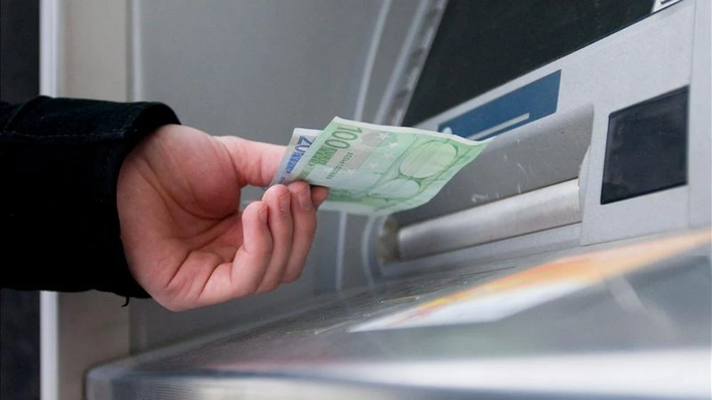 Un hombre saca euros de un cajero automático Un hombre saca euros de un cajero automático