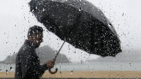 Un hombre pasea con lluvia junto a la bahía de La Concha de San Sebastián. Un hombre pasea con lluvia junto a la bahía de La Concha de San Sebastián.