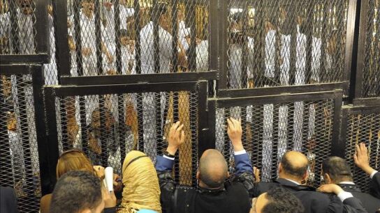 Varias personas se asoman a trav&eacute;s de las rejas de la jaula en la que fueron recluidos los 75 egipcios acusados por la matanza