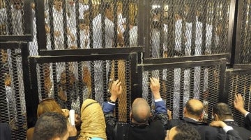 Varias personas se asoman a través de las rejas de la jaula en la que fueron recluidos los 75 egipcios acusados por la matanza