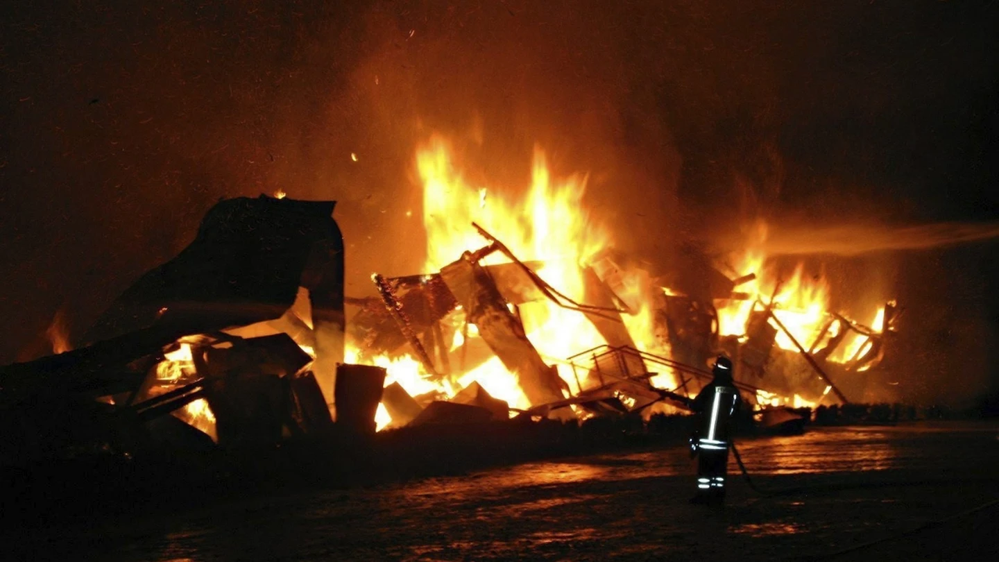 Un bombero tratando de controlar el fuego, durante un incendio en una granja de camellos. Un bombero tratando de controlar el fuego, durante un incendio en una granja de camellos.