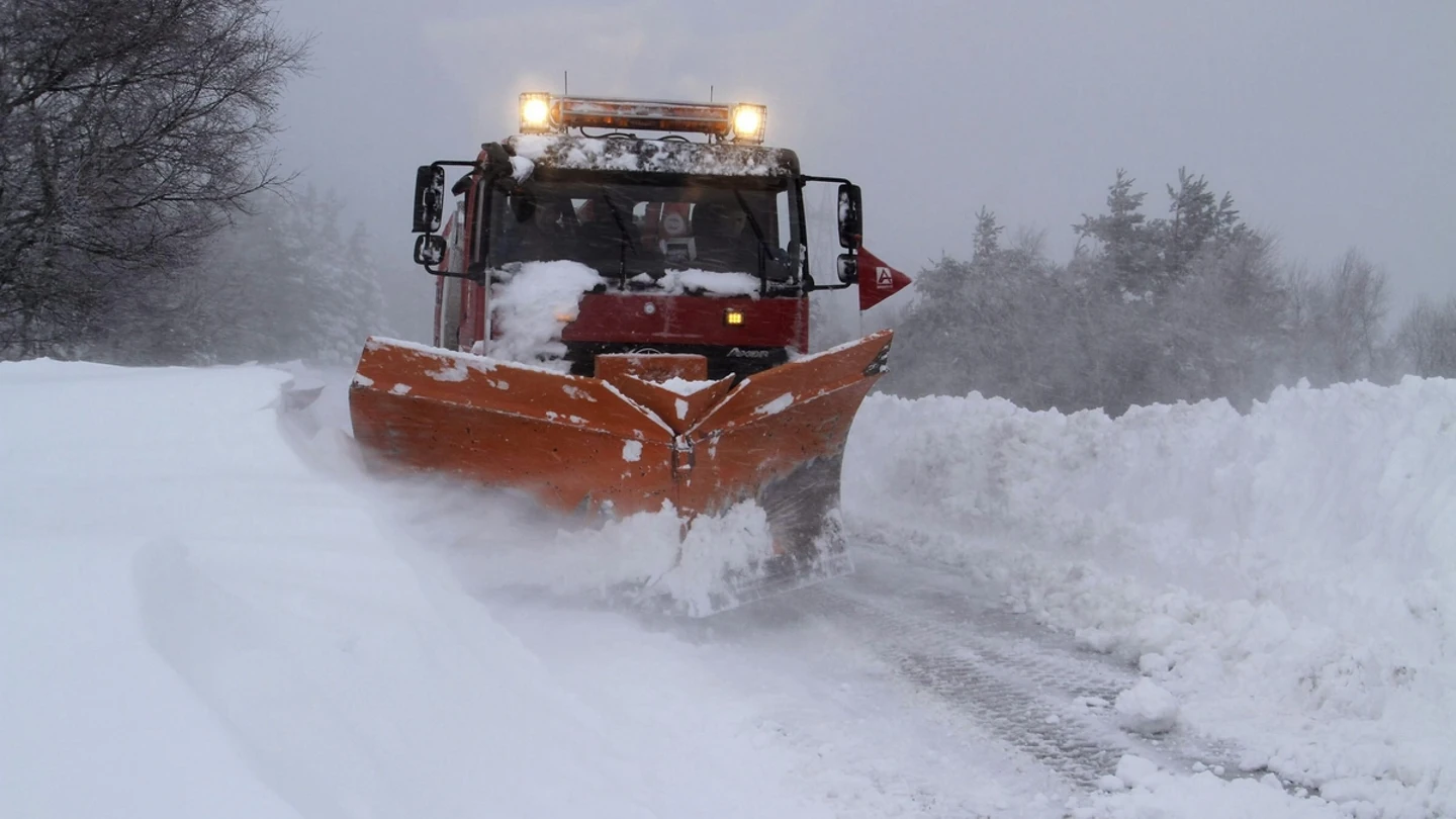 Un camión quitanieves retira la nieve acumulada en una carretera. Un camión quitanieves retira la nieve acumulada en una carretera.