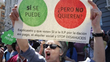 Una mujer sostiene una pancarta durante la concentración convocada por la PAH frente al Congreso.