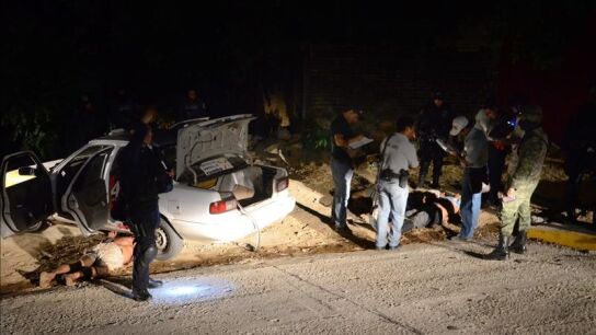 Agentes estatales y peritos forenses investigan la zona donde fueron localizados los cuerpos.