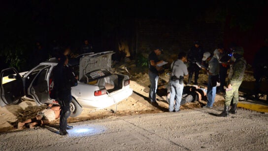 Agentes estatales y peritos forenses investigan la zona donde fueron localizados los cuerpos.