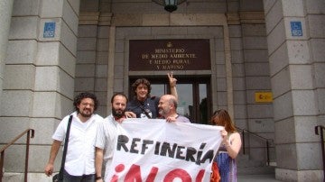 Cinco personas muestran una pancarta en la que rechazan la refinería