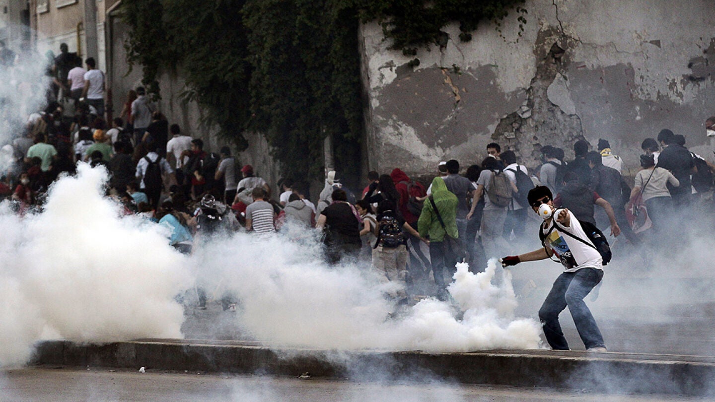 Un manifestante devuelve un gas lacrim&oacute;geno disparado por antidisturbios.