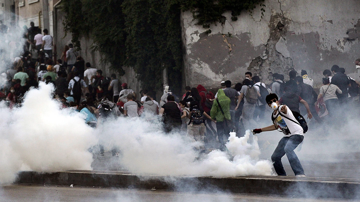 Un manifestante devuelve un gas lacrimógeno disparado por antidisturbios. Un manifestante devuelve un gas lacrimógeno disparado por antidisturbios.