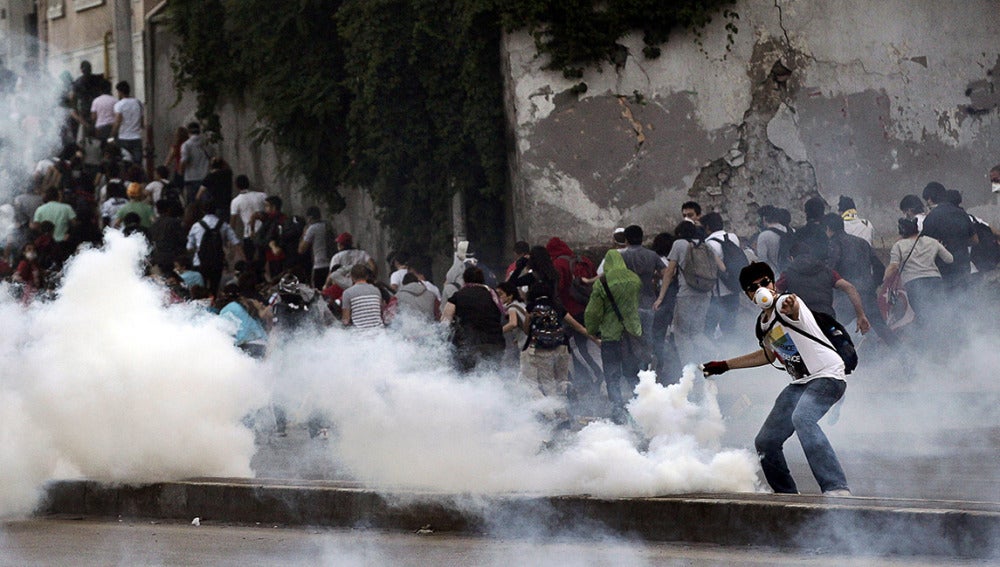 Un manifestante devuelve un gas lacrimógeno disparado por antidisturbios.