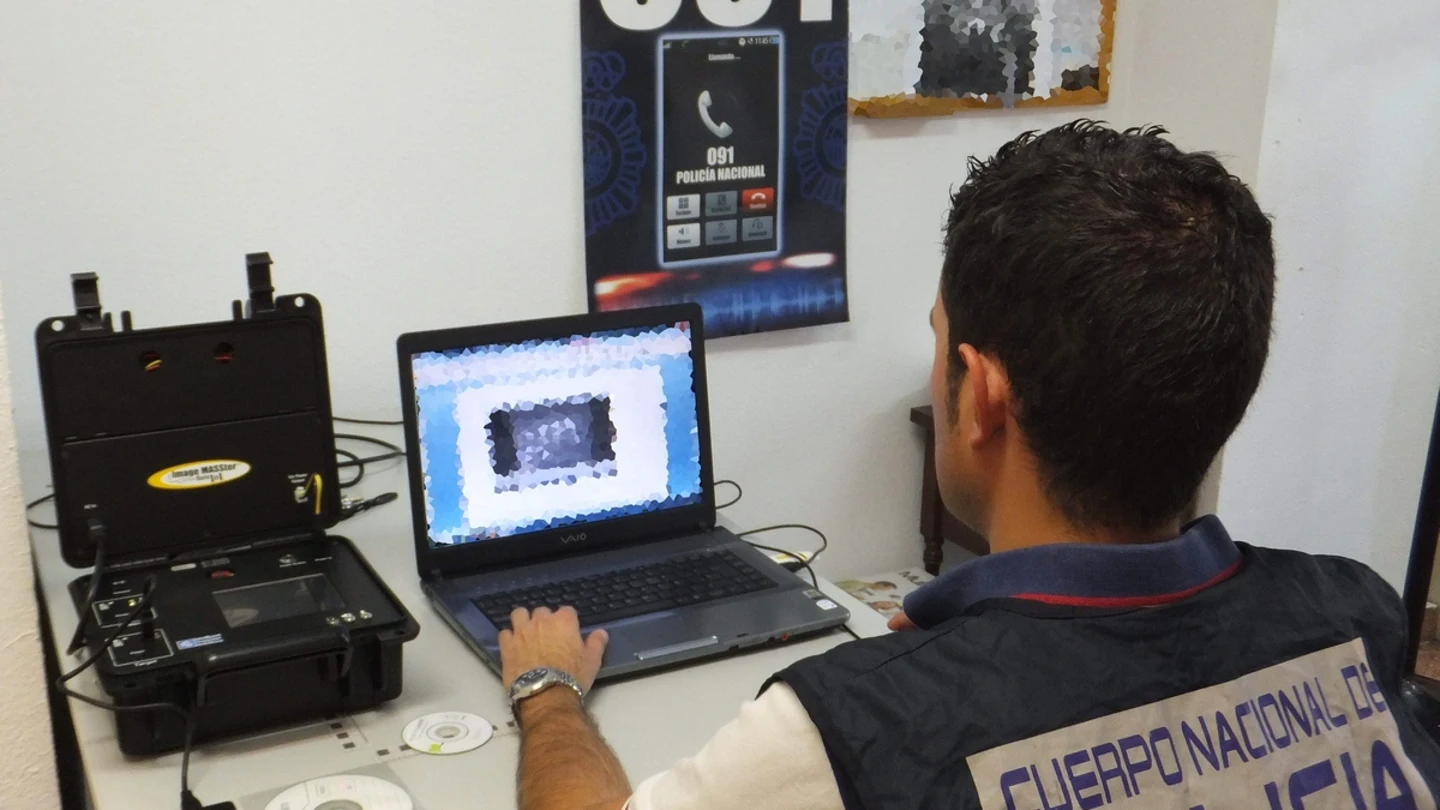 Agente analizando material pedófilo incautado al detenido. Agente analizando material pedófilo incautado al detenido.