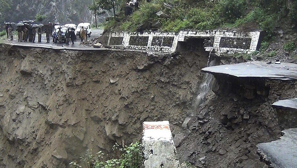 Varias personas observan una carretera destrozada por las lluvias torrenciales en Badrinath
