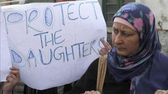 Una mujer sostiene un cartel en el que pide protecci&oacute;n para las mujeres j&oacute;venes