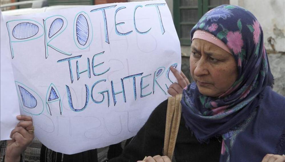 Una mujer sostiene un cartel en el que pide protección para las mujeres jóvenes