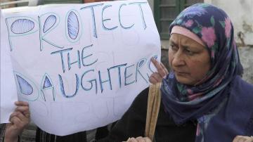 Una mujer sostiene un cartel en el que pide protección para las mujeres jóvenes