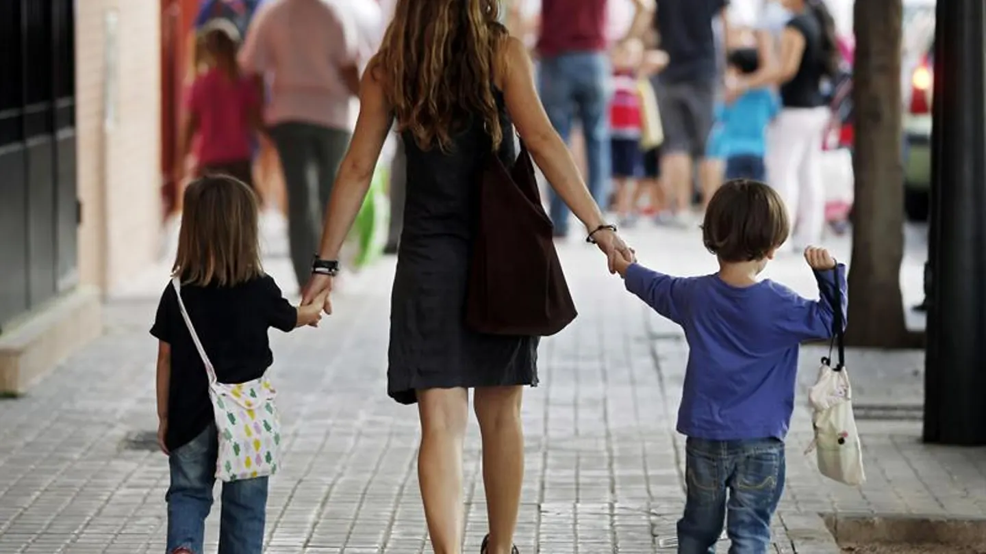 Una madre se dirige con sus hijos al colegio Una madre se dirige con sus hijos al colegio