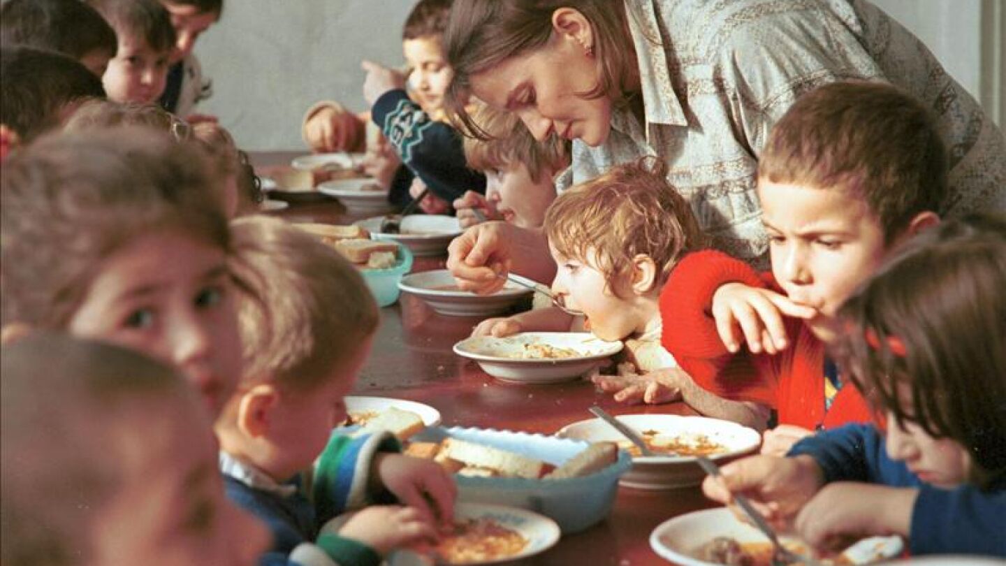 Una mujer ayuda a comer a un ni&ntilde;o en un orfanato en Rusia.