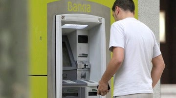 Un hombre saca dinero de un cajero automático. 