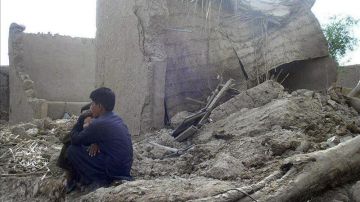 Varias personas permanecen junto a sus casas en ruinas tras el terremoto en Awaran 