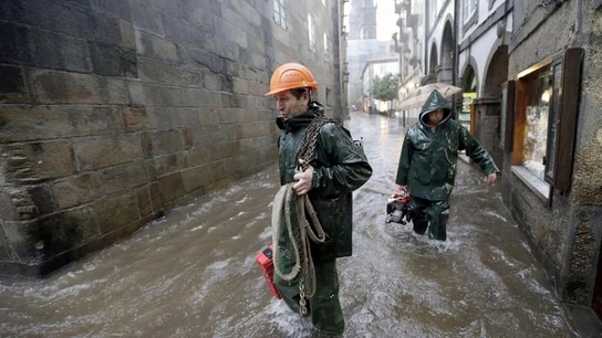 Miembros de los servicios de emergencias caminan por una calle del casco histórico de Santiago de Compostela, tras la tromba de agua caída en la capital Miembros de los servicios de emergencias caminan por una calle del casco histórico de Santiago de Compostela, tras la tromba de agua caída en la capital