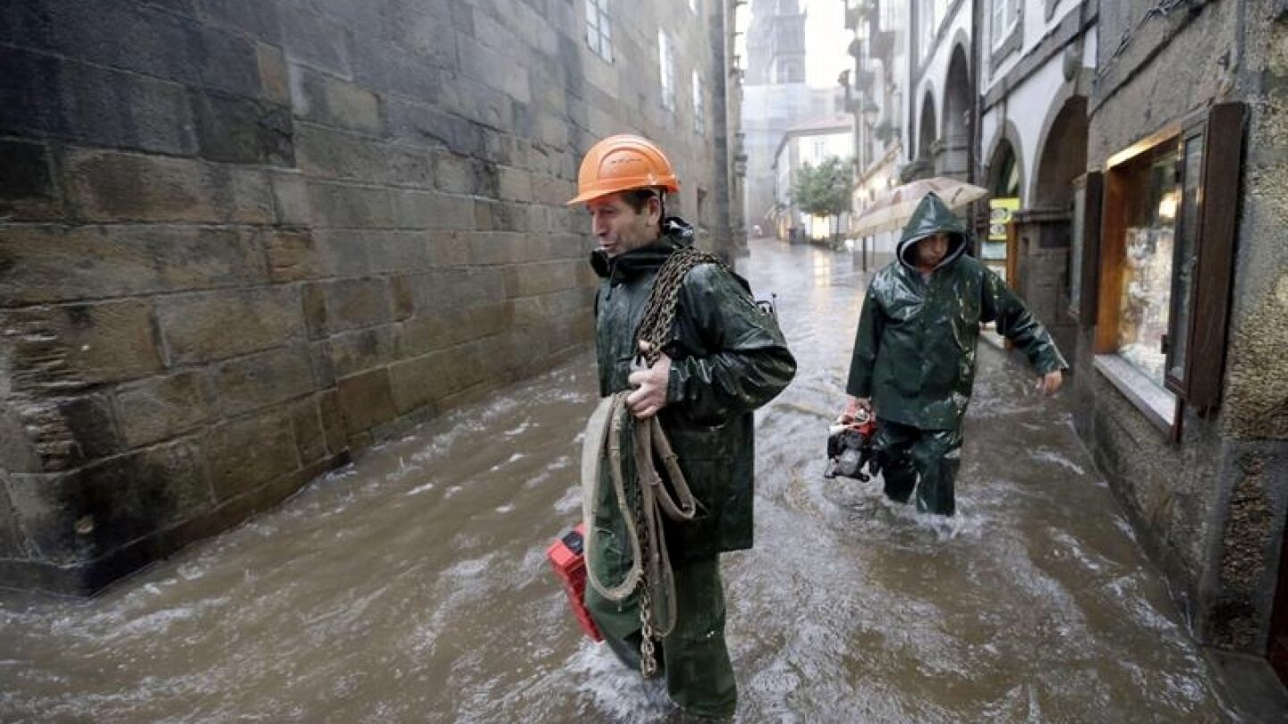 Miembros de los servicios de emergencias caminan por una calle del casco hist&oacute;rico de Santiago de Compostela, tras la tromba de agua ca&iacute;da en la capital 