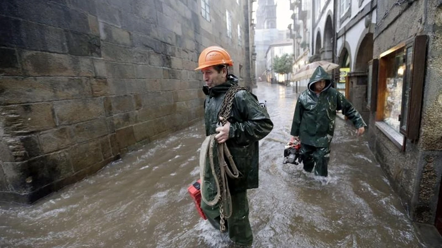 Miembros de los servicios de emergencias caminan por una calle del casco histórico de Santiago de Compostela, tras la tromba de agua caída en la capital Miembros de los servicios de emergencias caminan por una calle del casco histórico de Santiago de Compostela, tras la tromba de agua caída en la capital