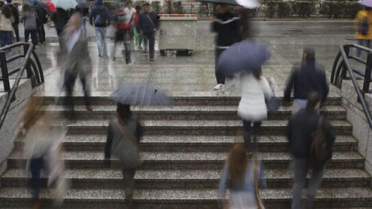 Un grupo de personas sale del metro bajo la lluvia