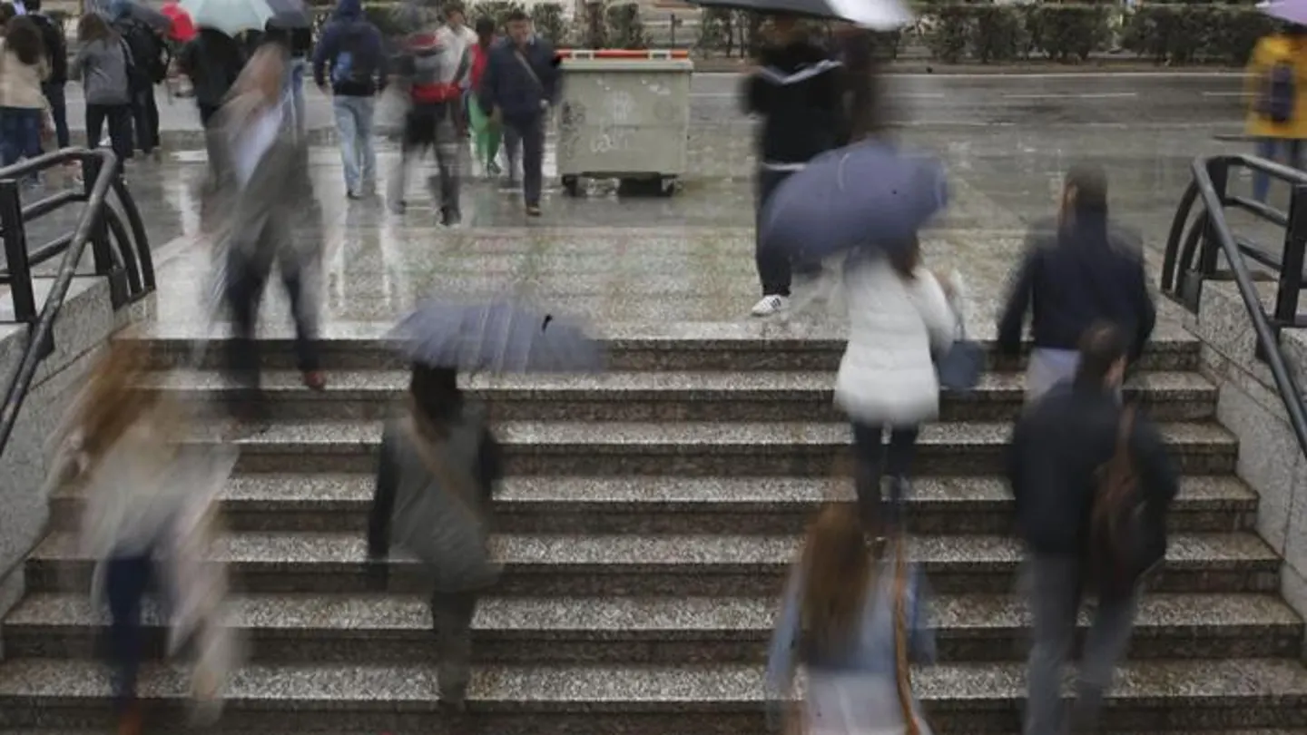 Un grupo de personas sale del metro bajo la lluvia Un grupo de personas sale del metro bajo la lluvia