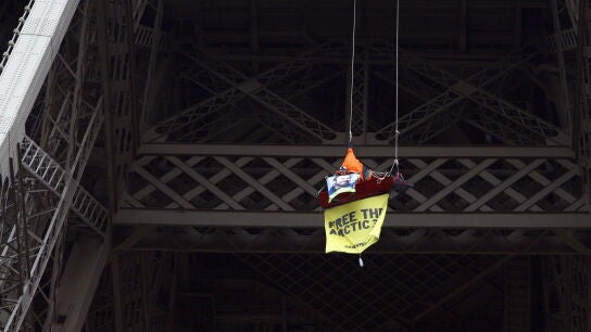 Una activista colgada del segundo piso de la Torre Eiffel en Par&iacute;s durante una protesta