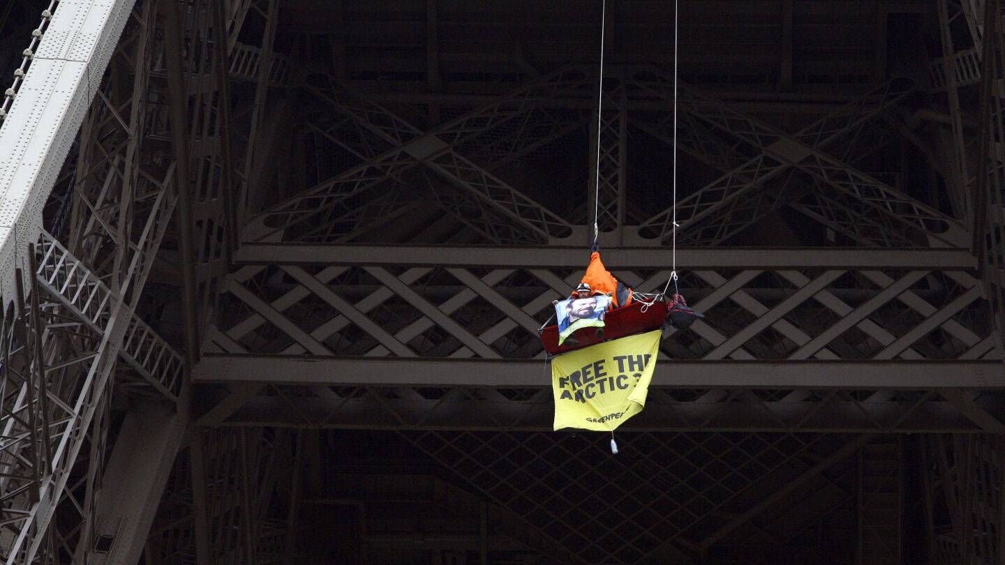 Una activista colgada del segundo piso de la Torre Eiffel en Par&iacute;s durante una protesta