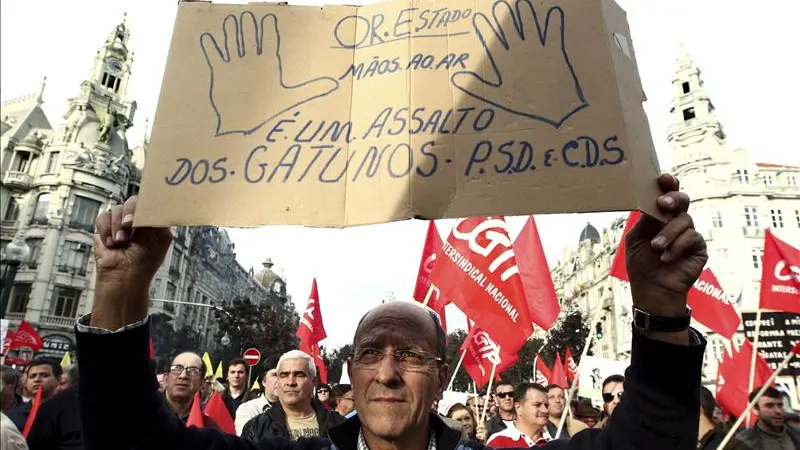 Un hombre sostiene una pancarta en la que se lee "Presupuestos generales del Estado, manos arriba