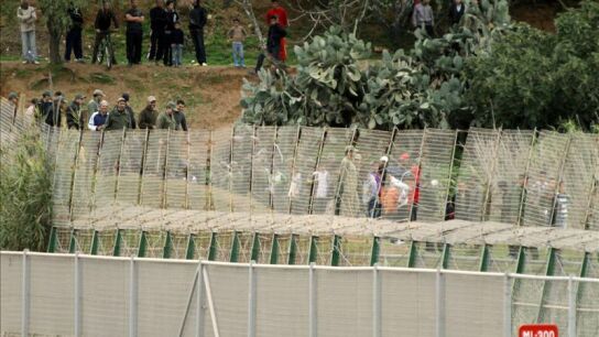 Varias personas junto a la valla de Melilla