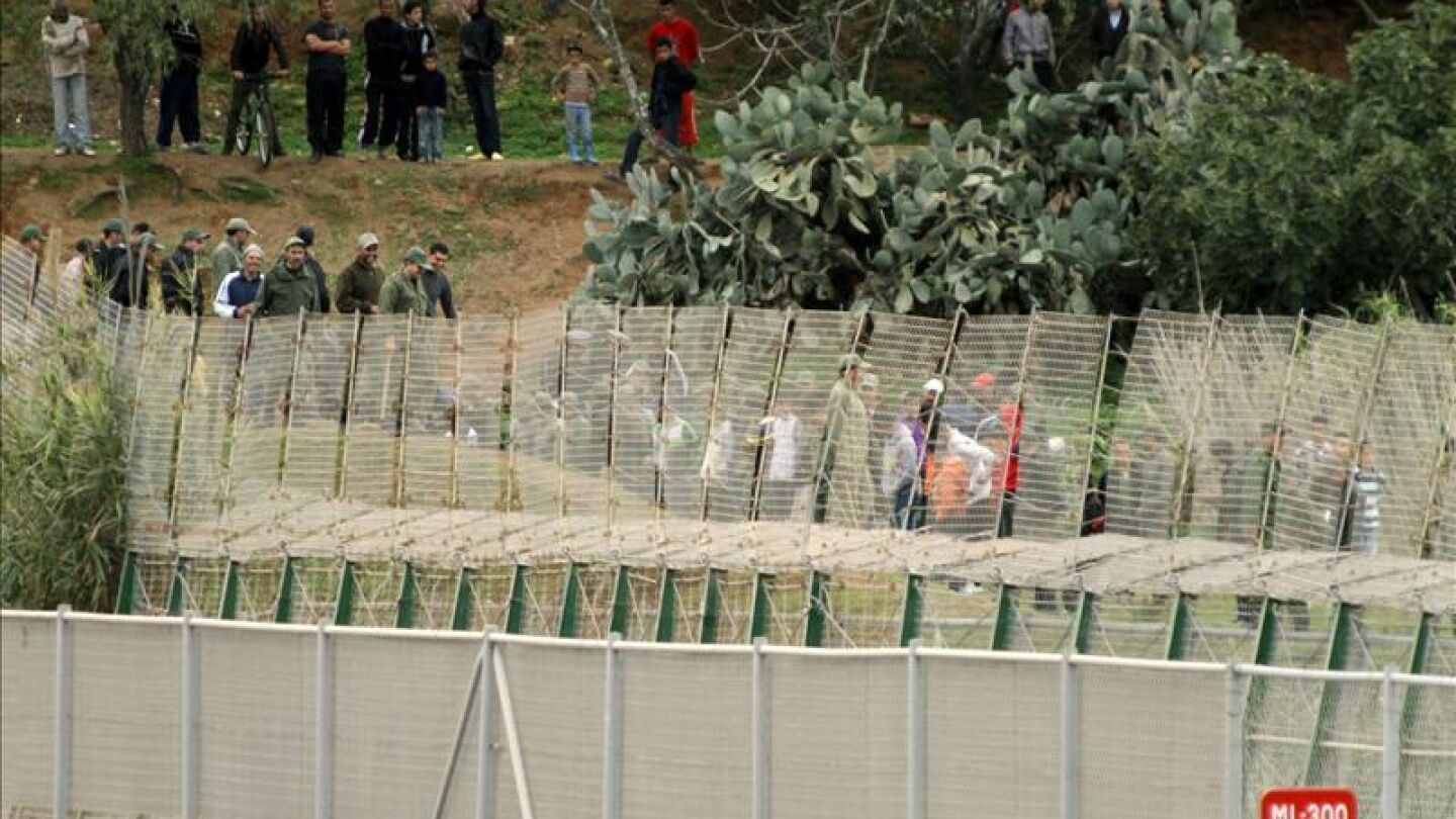 Varias personas junto a la valla de Melilla