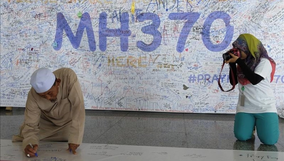 Un hombre escribe una dedicatoria en uno de los murales que se han ido creando en homenaje a los pasajeros del avión