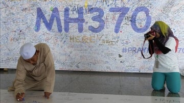 Un hombre escribe una dedicatoria en uno de los murales que se han ido creando en homenaje a los pasajeros del avión