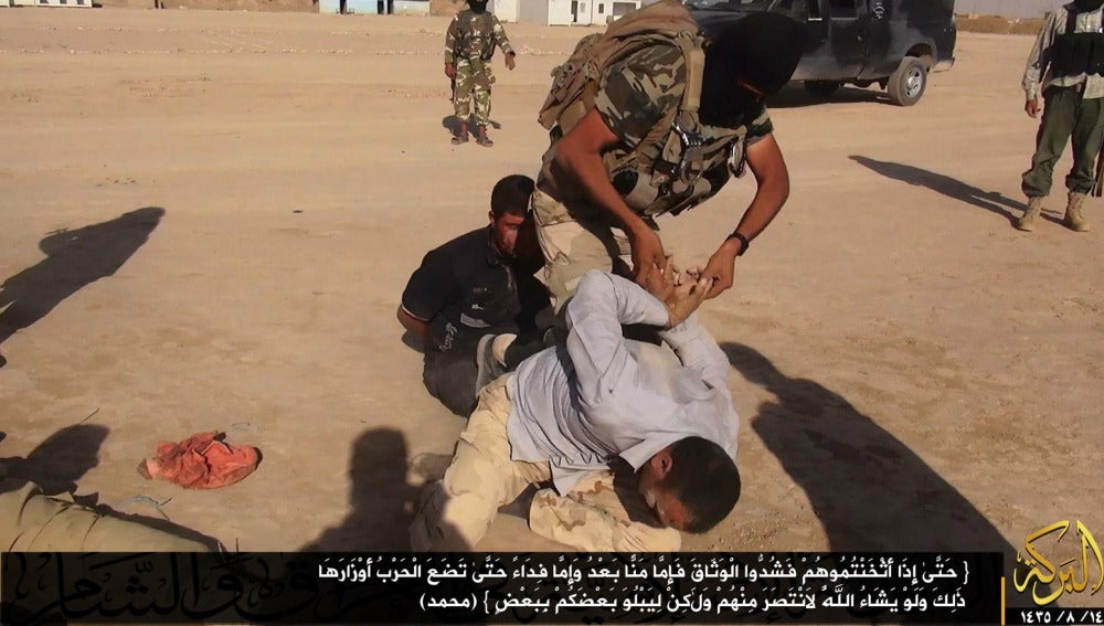 Un militante del grupo ISIS atando las muñecas de un soldado iraquí
