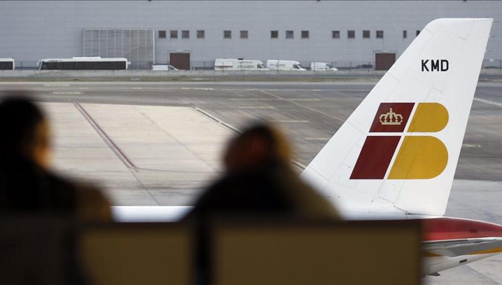 Dos pasajeros contemplan un avión de Iberia