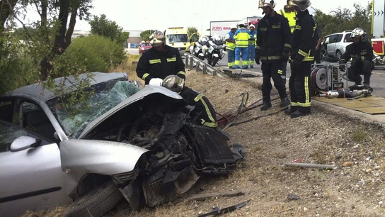 Los bomberos junto a un coche siniestrado Los bomberos junto a un coche siniestrado