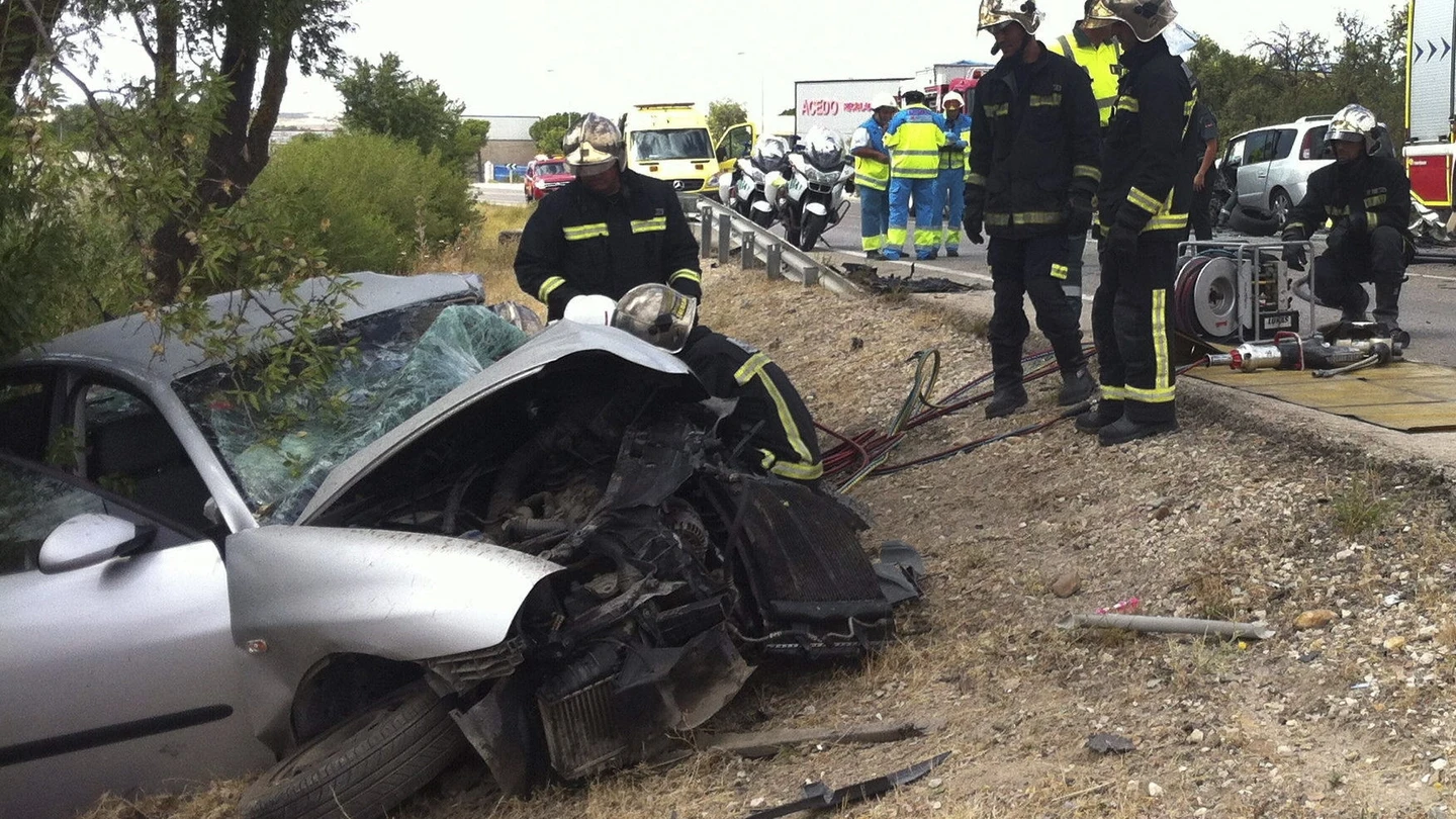 Los bomberos junto a un coche siniestrado Los bomberos junto a un coche siniestrado