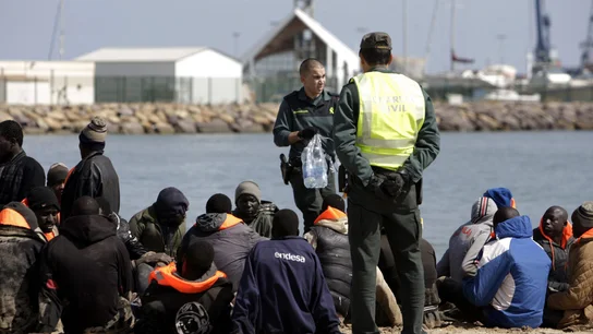 Dos miembros de la Guardia Civil junto al grupo de 25 inmigrantes Dos miembros de la Guardia Civil junto al grupo de 25 inmigrantes