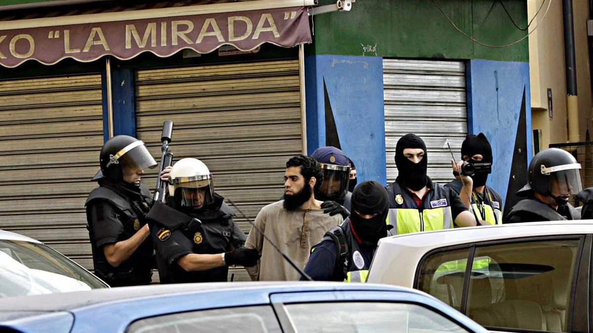 Agentes de policía junto a uno de los detenidos