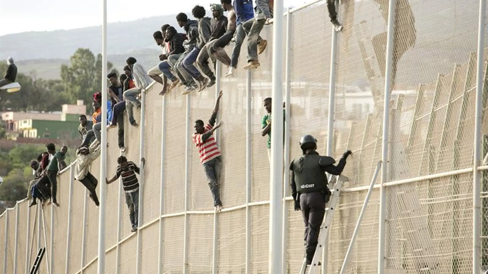 Inmigrantes encaramados en la valla de Melilla (Archivo)