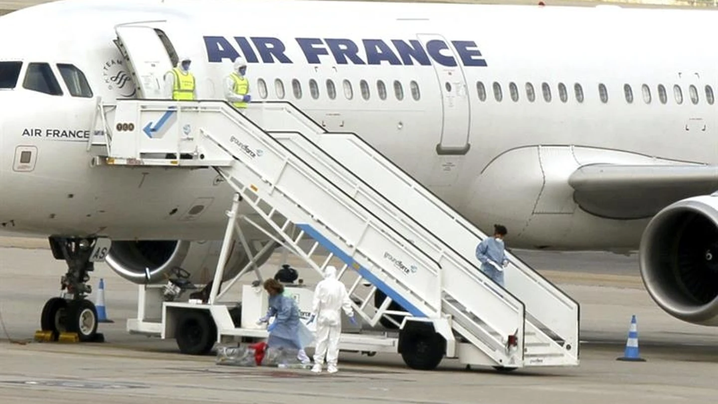 El avión en pista y personal sanitario con trajes de protección El avión en pista y personal sanitario con trajes de protección