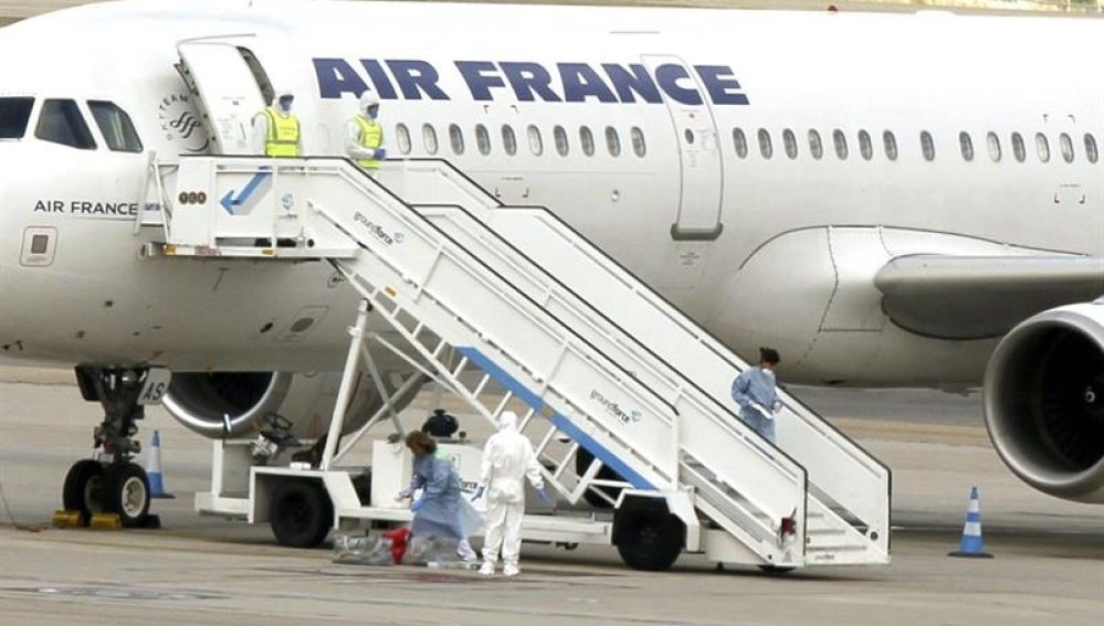 El avión en pista y personal sanitario con trajes de protección