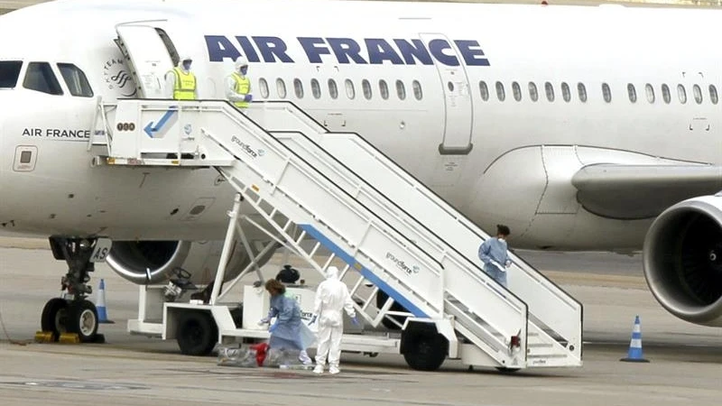 El avión en pista y personal sanitario con trajes de protección