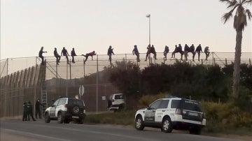 Una quincena de inmigrantes permanecen encaramados en la valla